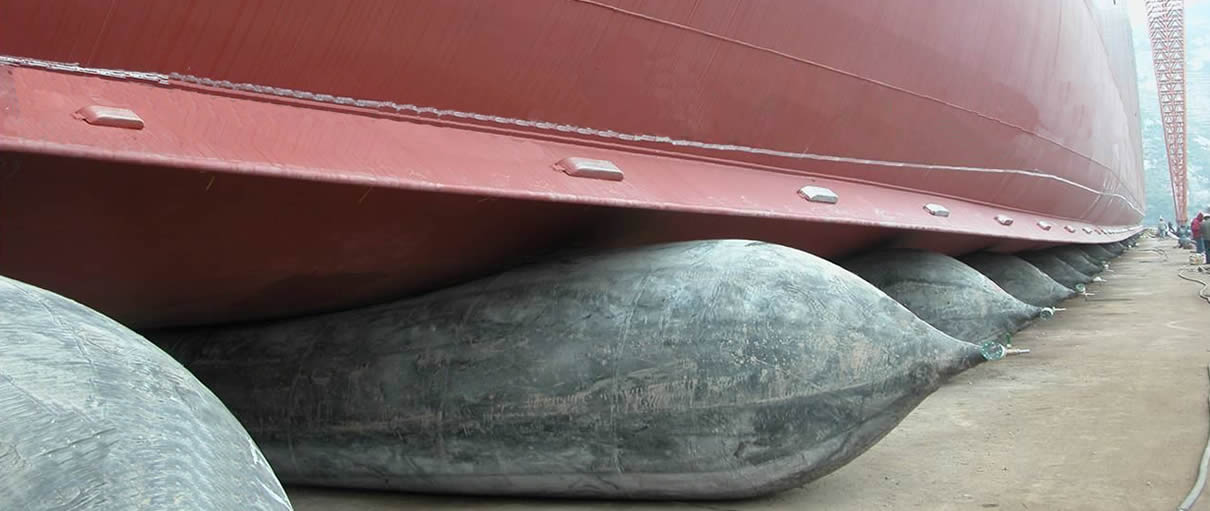 A row of black marine airbags are used to launch a red vessel