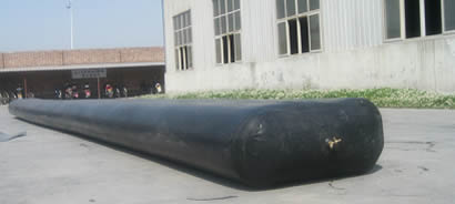 A black elliptical inflatable rubber mandrel is on the ground.