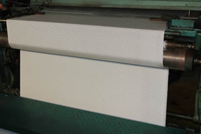 A set of equipment is producing gray fabric.