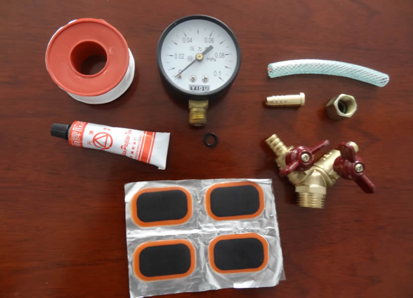 A heap of inflatable rubber mandrel fittings are on the table, including air value, pressure gauge, glue and tire piece.