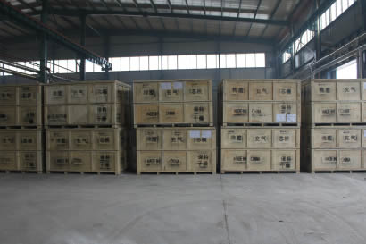 Many wooden boxes containing round inflatable rubber mandrels are on the floor of the warehouse.