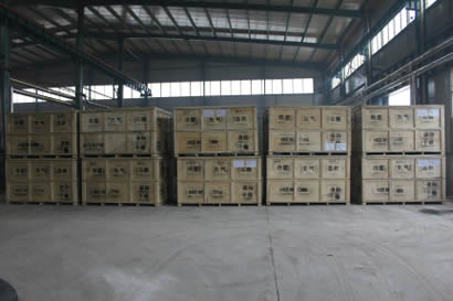 Many wooden boxes containing rubber products are on the floor of the warehouse.