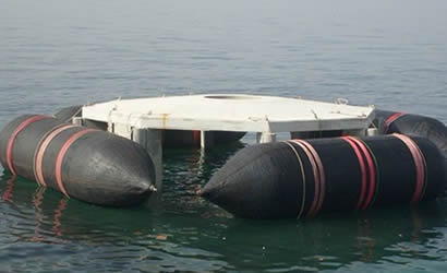 Four black marine salvage airbags are used to support floating structures.