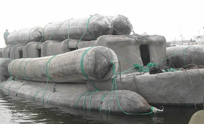 Various black marine salvage airbags are used to transport heavy products.